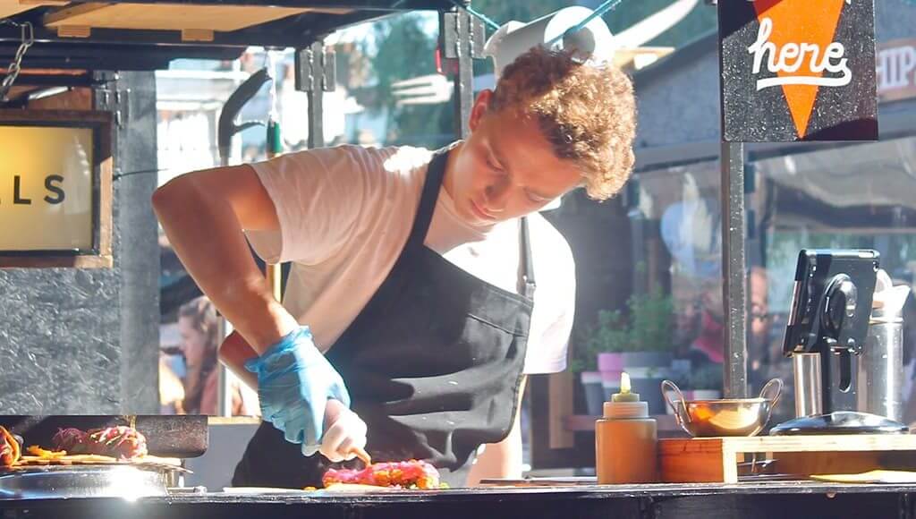 6 Lessons I Learned Setting Up a Street Food Stall image - young male chef creating a hotdog in a popup food stall