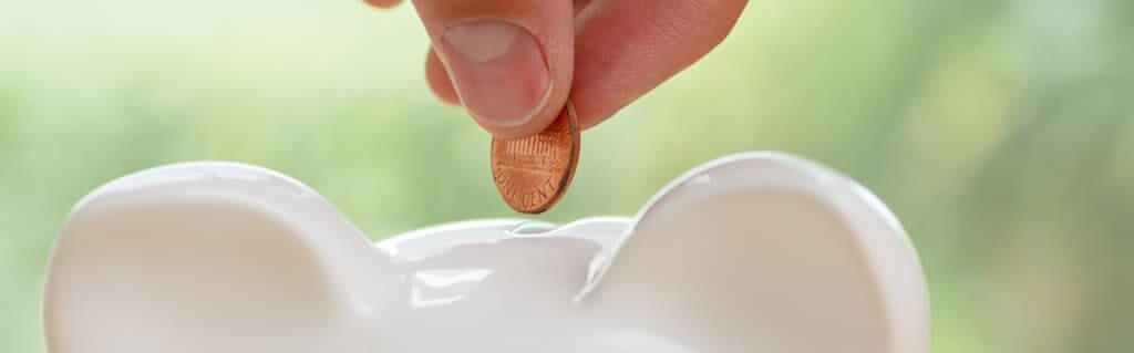 Close up of a coin being inserted into a saving piggy bank