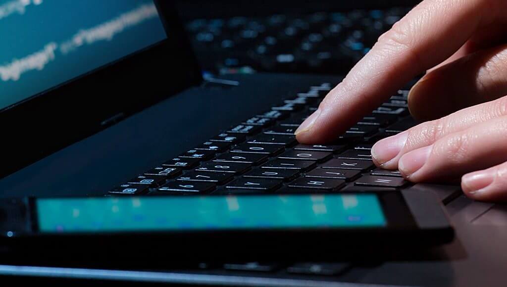 Spot The Red Flags: How To Protect Your Business From Cyberattacks image - hacker typing code into a black laptop