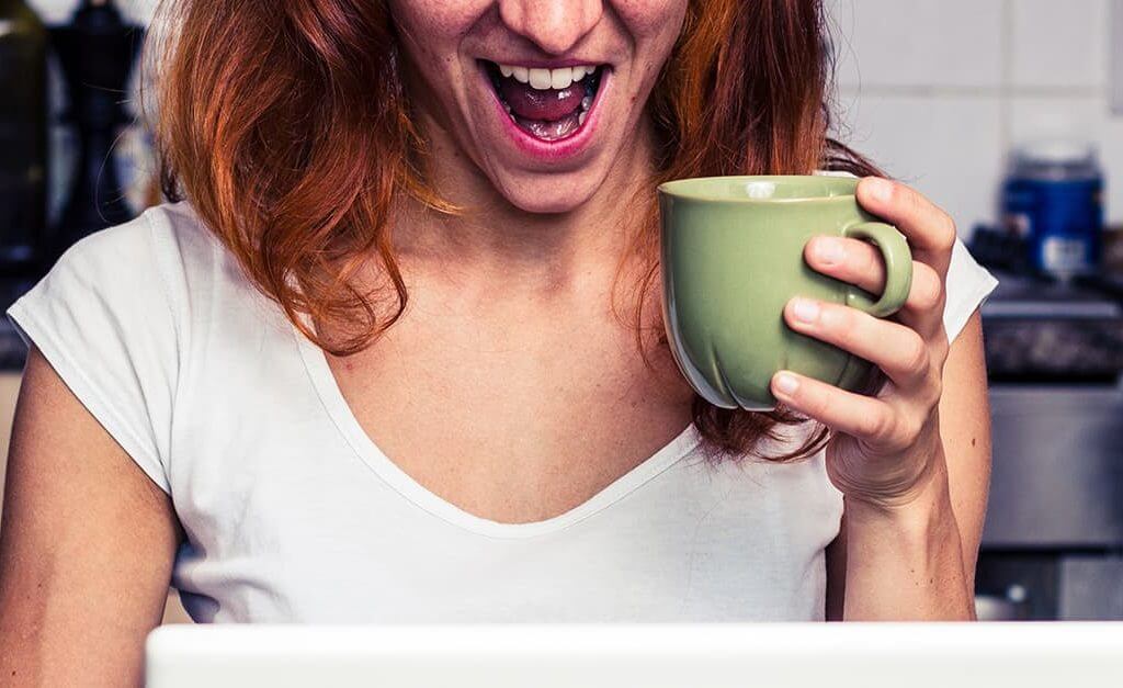 Ecstatic mumpreneur in the kitchen holding a coffee cup